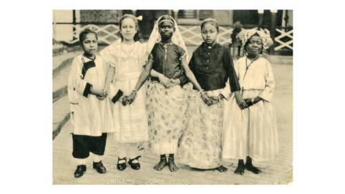 Oorspronkelijke tekst bij de foto: "Deze vijf meisjes zijn bij de soeurs in 't weeshuis. Van links naar rechts: Chinees, Blanke, Brits-Indische, Javaanse, Negerin." Suriname, jaartal onbekend. (Bron: Collectie Fraters van Tilburg / Stadsmuseum Tilburg inv. nr. 411331)