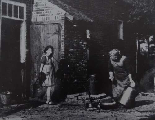 Mimi de Rooy komt omstreeks 1952 net aangelopen bij het wassen van het melkgerei door Grarda Leyten (rechts op foto). (Foto: Collectie Erfgoedvereniging Kèk Liemt)