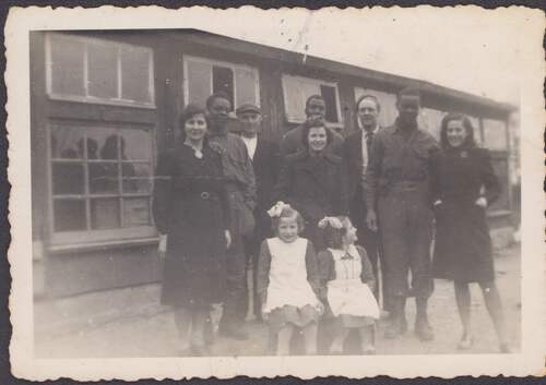 Foto van de familie Van de Vossenberg met Afro-Amerikaanse soldaten en een onderduiker, gemaakt voor hun oude kippenschuur tijdens de Tweede Wereldoorlog (Foto: Privécollectie Wim van de Vossenberg, oktober 1944)